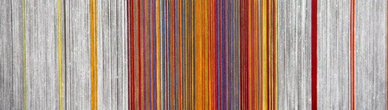 Verschiedenfarbige Fäden, die auf einem Webstuhl nebeneinanderliegen