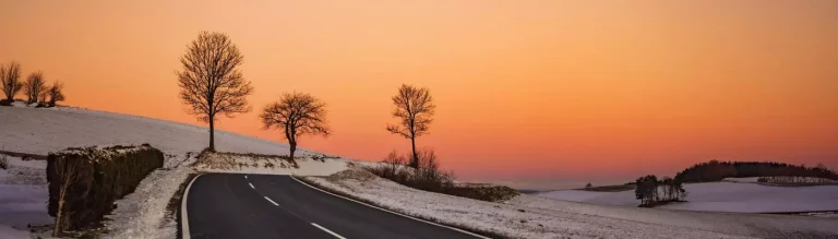 Straße im Winterfrost führt in Sonnenaufgang