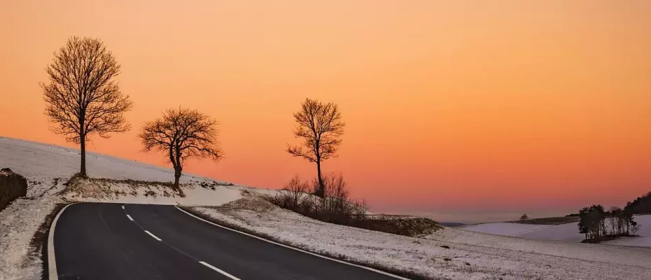 Straße im Winterfrost führt in Sonnenaufgang